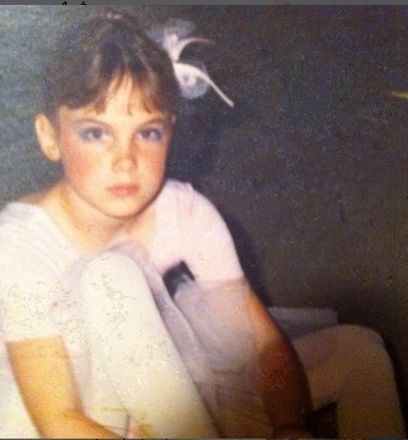 Childhood picture of Amanda Walsh posing for a photoshoot wearing white color dress